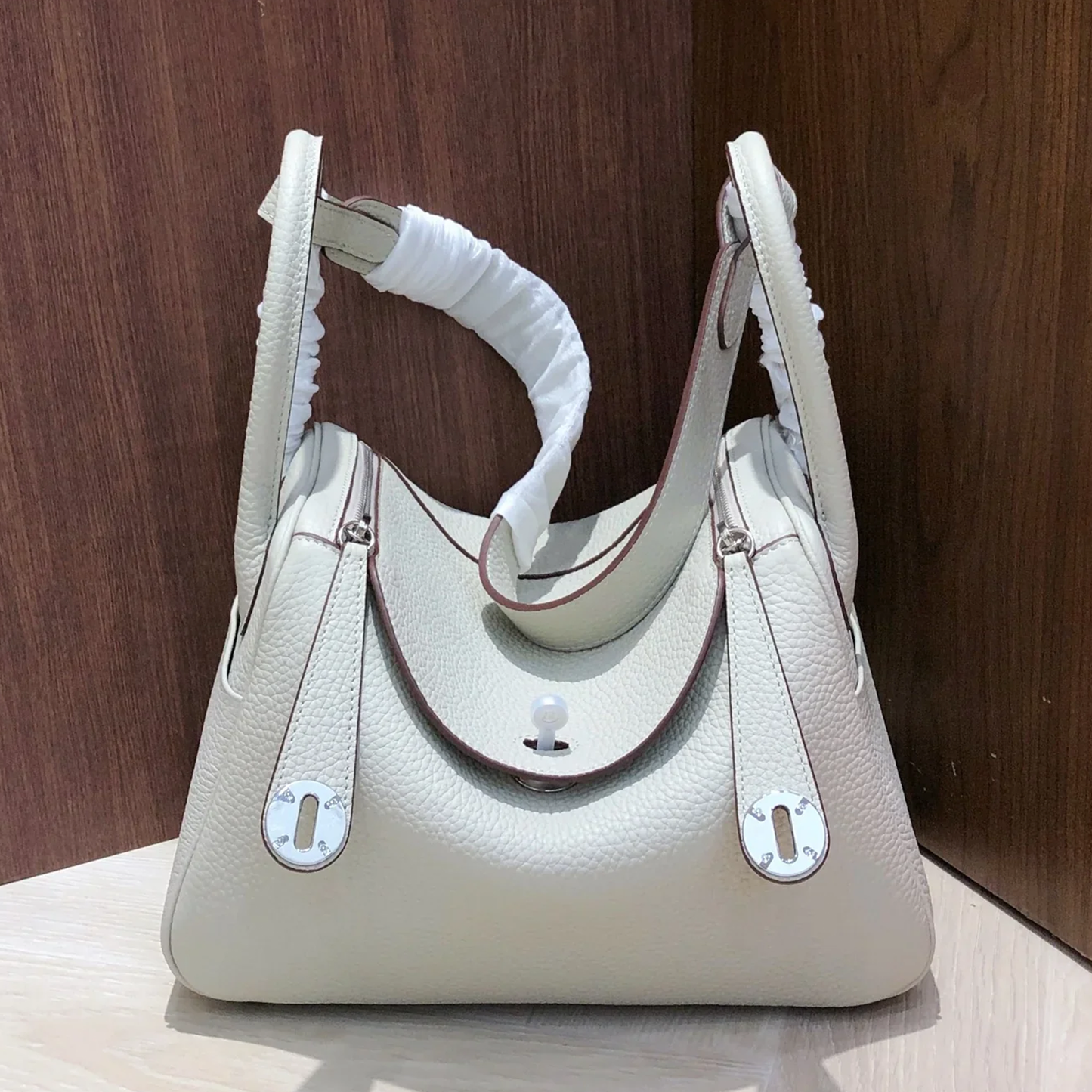 Pale Milky Off White Pebble Grain Rounded Compact Shoulder Bag With Polished Silvery Turn Lock Hardware And Blush Toned Inner Lining